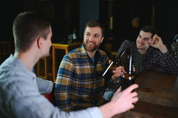 Friends resting in the pub with beer in hands. Having conversation.
