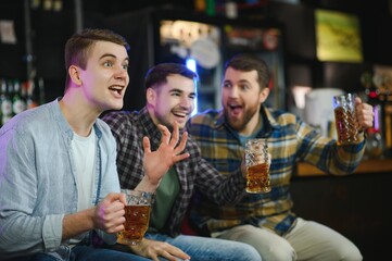 Soccer fans at the bar. Happy football fans cheering at bar and drinking beer while bartender serving beer at the background