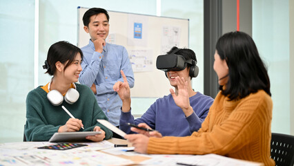 A male developer sitting at the table tested a new VR game with virtual reality goggles