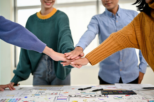A close-up image of a team of developers or graphic designers putting their hands together
