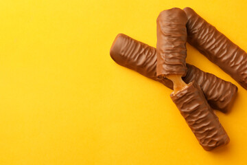 Sweet tasty chocolate bars with caramel on yellow background, flat lay. Space for text