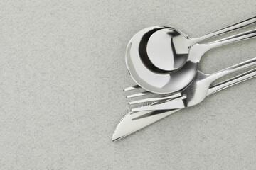 Fork, knife and spoons on grey background, flat lay with space for text. Stylish cutlery set