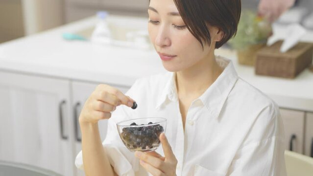 ブルーベリーを食べる若い女性　飲食イメージ