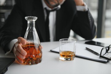 Old male employee drinking alcohol at workplace