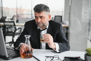 Old business man is drinking alchool at the office