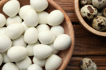 Unpeeled and peeled boiled quail eggs on wooden table, flat lay