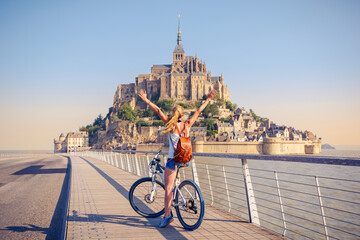 Woman with bicycle in Mont Saint Michel- Normandie in France - obrazy, fototapety, plakaty