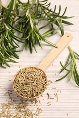 Spoon with dry rosemary and fresh twigs on white wooden table, above view