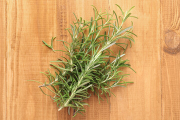 Sprigs of fresh rosemary on wooden table, top view