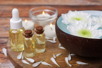 Beautiful composition with bowl of water, flowers and essential oils on table, closeup. Spa treatment