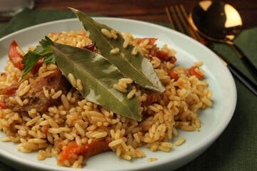 Delicious pilaf and bay leaves on plate, closeup