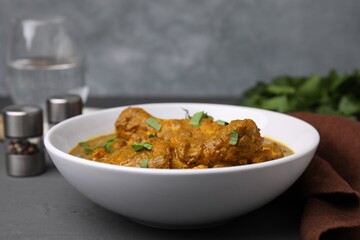 Delicious chicken with curry sauce on grey wooden table, closeup