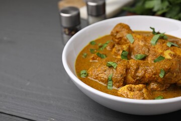 Delicious chicken with curry sauce on grey wooden table, closeup. Space for text
