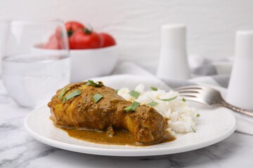 Delicious rice and chicken with curry sauce served on white marble table, closeup