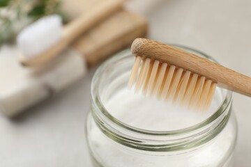 Fototapeta na wymiar Bamboo toothbrush and jar of baking soda on table, closeup