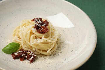 Tasty spaghetti with sun-dried tomatoes and parmesan cheese on table, closeup. Exquisite presentation of pasta dish