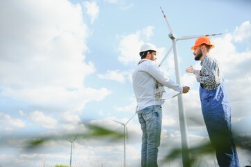 Young maintenance engineer team working in wind turbine farm.