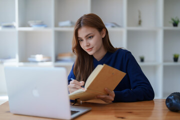 Happy latin girl college student watching distance online learning class, remote university webinar or having talk on laptop video call and use notebook to virtual meeting seminar at home or campus.