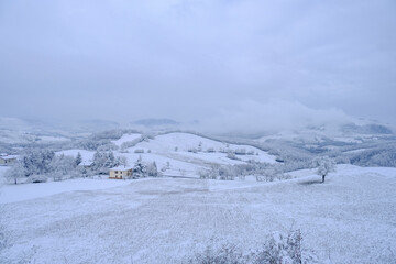 Fototapeta na wymiar Blizzard in the mountains. Snowy hills, mountains, village, nature, horizon. Natural background. Appennino-Tosco-emiliano 