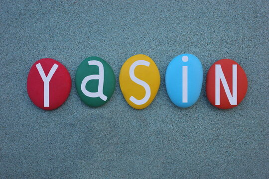 Yasin, turkish masculine given name composed with multi colored stone letters over green sand