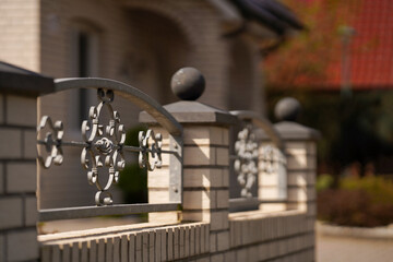 Brick fence with forged iron lattice. Rural landscape, soft focus.