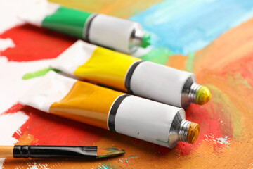 Tubes of colorful oil paints and brush on canvas with abstract painting, closeup