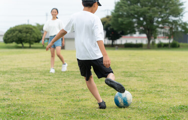 公園でサッカーをするアジア人の子供