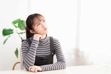 部屋で考え事をしている若い女性