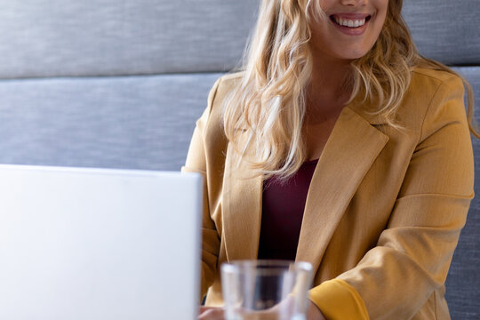 Mid section of smiling plus size caucasian casual businesswoman using laptop at desk