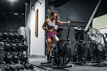 woman doing cardio on the crossfit bike - Powered by Adobe