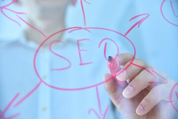 Hand with red pen writing SEO concep