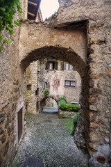 Fototapeta na wymiar Via Fratelli Bandiera, a narrow lane through tunnel arches, Canale di Tenno, Trentino-Alto Adige, Italy. Tenno is included in the list of the most beautiful villages in Italy