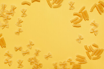 
frame of different types of italian pasta on a yellow background. copy space.