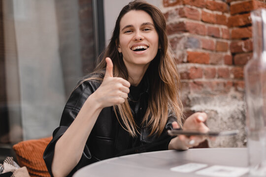 Woman scanning the barcode qr code in restaurant. Blonde woman use her photo on mobile phone to pay by bills, watching menu or write response. Happy woman like new technology. Easy pay, thumb up, like