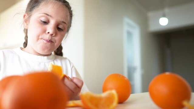 girl child eating oranges. dream happy family fruit healthy food kid concept indoors. little girl daughter eating oranges at the table in the kitchen. juicy fruits oranges are for a healthy diet