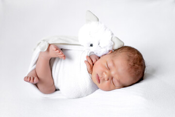 newborn baby girl in a diaper on a white background sleeping with a soft toy cat, the birth of a baby, a happy family