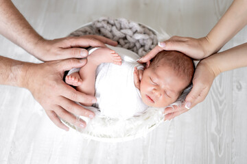 mom and dad's hands gently hold a sleeping newborn baby girl in a diaper on a white background, the birth of a baby, a happy family, a close-up of a child in parental hands