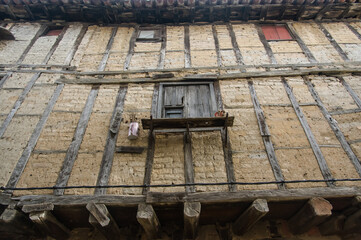 Fototapeta na wymiar Capture the rustic charm of an old house with clay-covered facade, showcasing exposed wooden beams and pillars. A glimpse into the architectural heritage of the past.