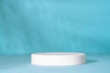 Podium for presentation cosmetic products on blue background. Palm leaves shadow.