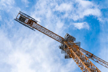 Yellow tower crane against blue sky. View from below.