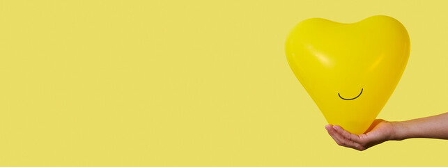 man holds a smiley yellow balloon, banner format