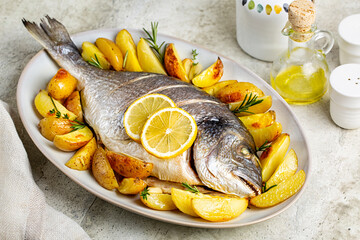 Meal with baked sea bream or dorada fish with baked potato, lemon and herbs. - obrazy, fototapety, plakaty