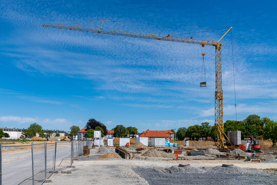 Construction site and yellow tower crane against a blue sky with light clouds.