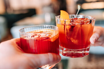 hands holding and clinking glasses cocktails in restaurant