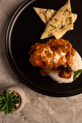 Butter Chicken with Rice and Naan Bread on a Black Plate 
