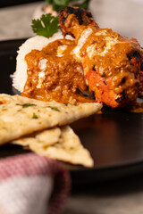 Butter Chicken with Rice and Naan Bread on a Black Plate 
