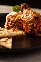 Butter Chicken with Rice and Naan Bread on a Black Plate 