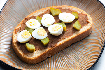 cracklings spread with pickled cucumber and boiled egg on slice of bread