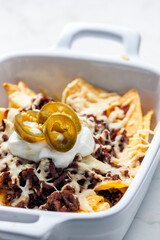 nachos with beef minced meat and cheese served with whipped cream and jalapenos