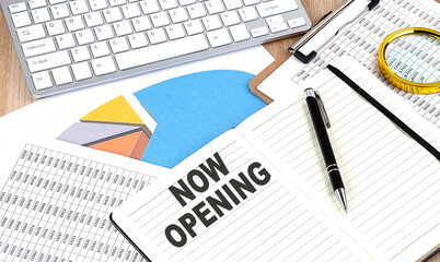 NOW OPENING text on notebook with chart and keyboard